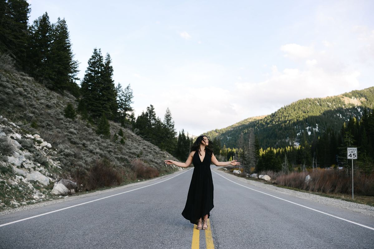 Chelsea Cerna standing on a mountain road, arms open